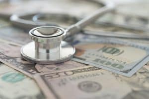 A stethoscope sits on top of $50 bills and $100 bills. The cost of Novolog can be an obstacle in the way of diabetics getting the insulin they need.