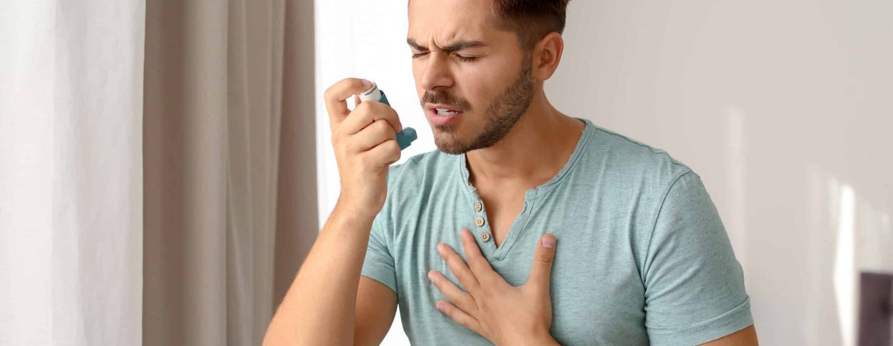 Young man using asthma inhaler at home